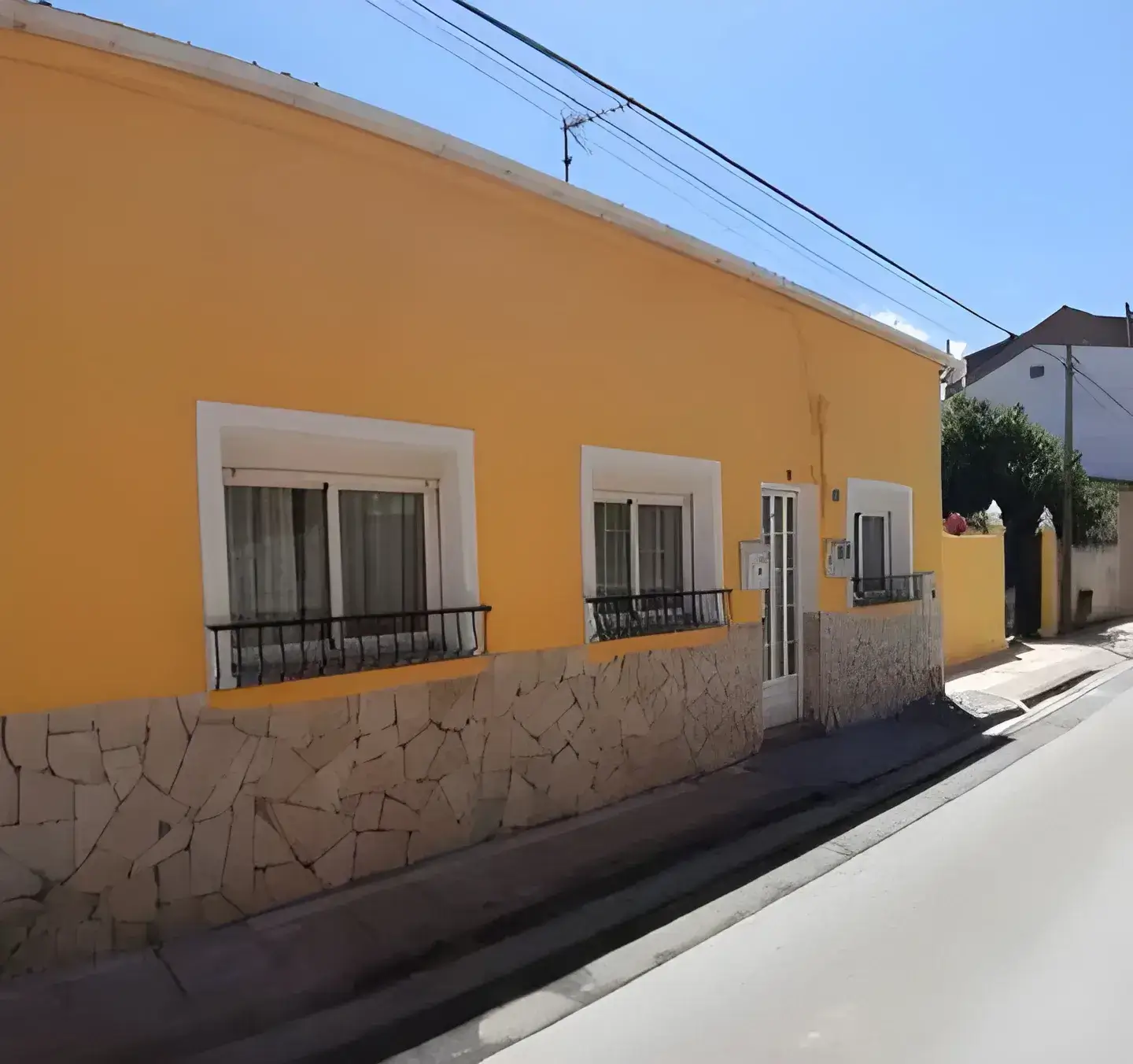Los Pintores Salamanca Fachada de casa tradicional pintada en color amarillo con zócalo de piedra